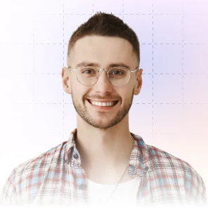 Smiling young man with short dark hair, glasses, and a plaid shirt against a light background.