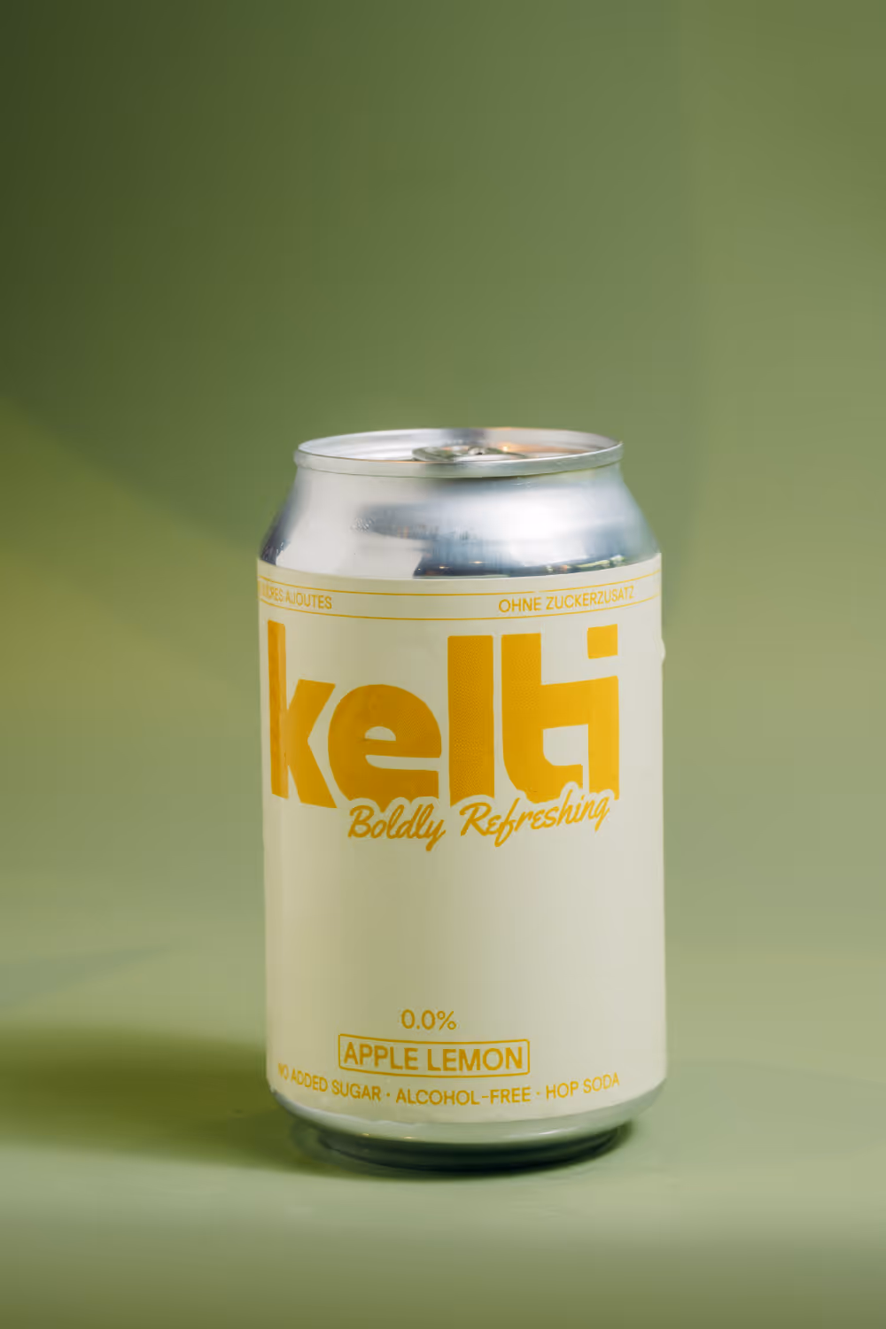Silver can of Kelti apple lemon hop soda with 0.0% alcohol and no added sugar on green background.