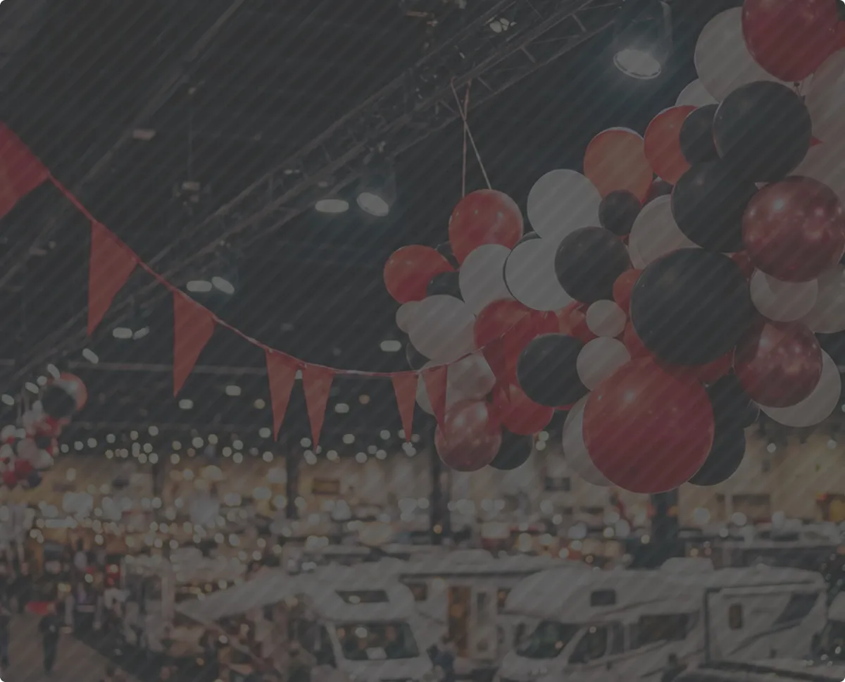 Red, white, and black balloons and red triangular flags decorating an indoor event space with RVs.