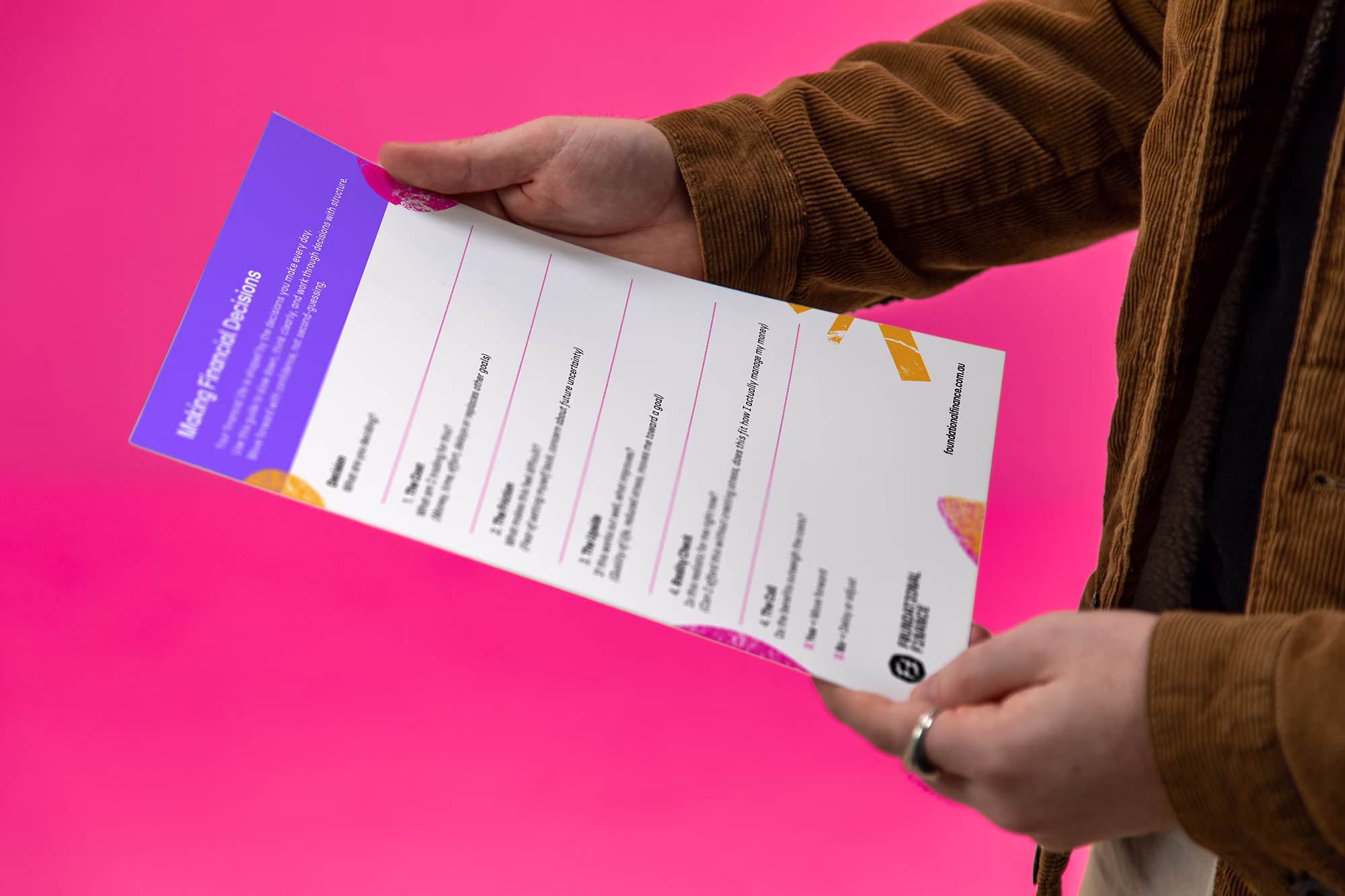 Person holding a financial planning worksheet titled 'Making Financial Decisions' with colorful border on pink background.