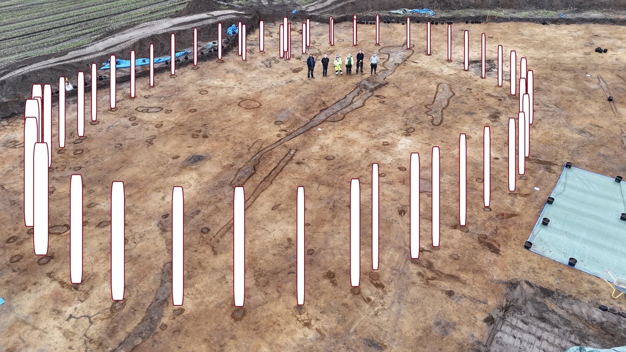 Dronefoto af en udgravning, hvor hvide markeringer viser en stor cirkel af stolpehuller
