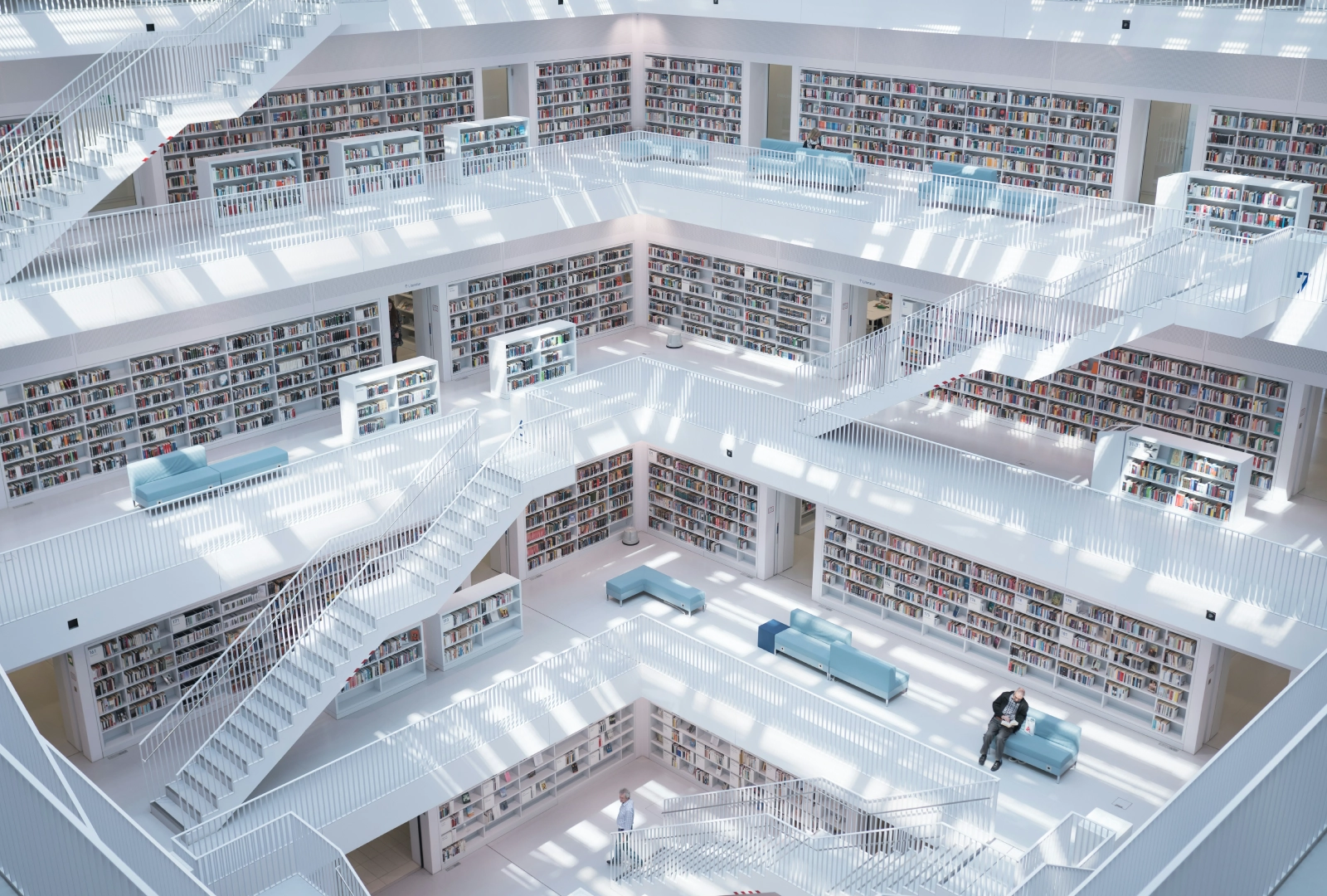 Bright multi-level library with white staircases and bookshelves