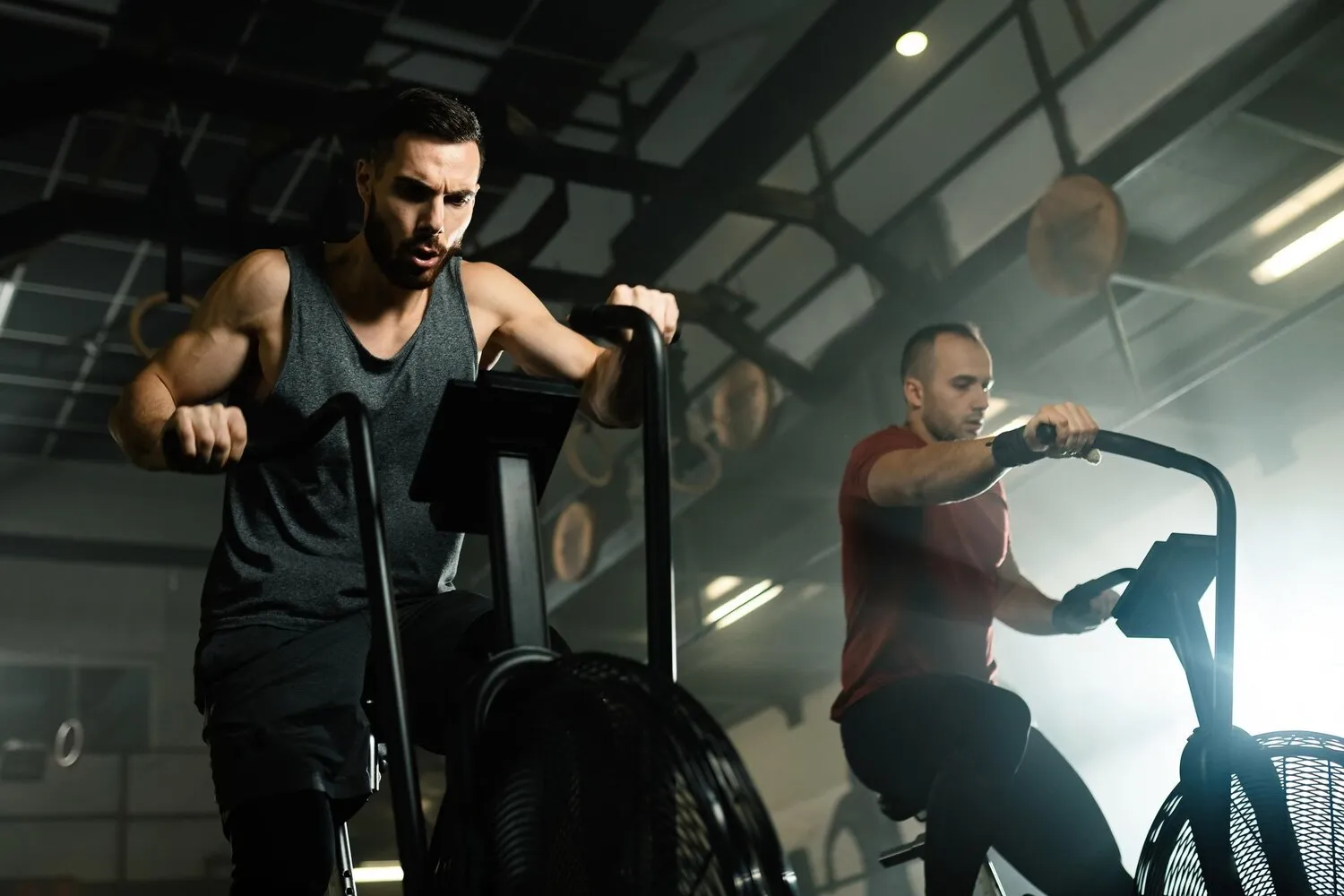 Man in black shirt holding orange dumbbells, looking focused during a workout.