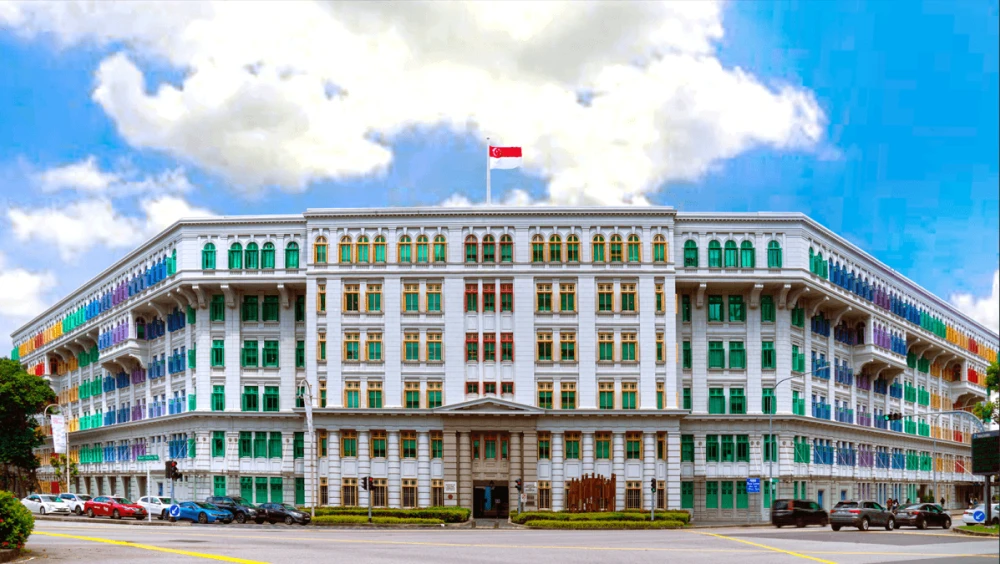 The Old Hill Street Police Station by day, its striking facade of multicoloured shutters stretching across six floors beneath the Singapore flag.