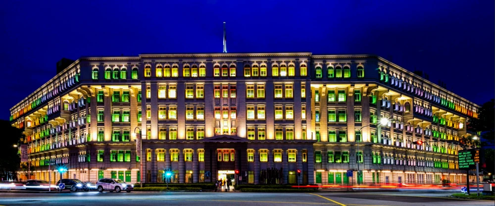 The Old Hill Street Police Station lit up at night, its rainbow-coloured window shutters glowing against a deep blue sky.