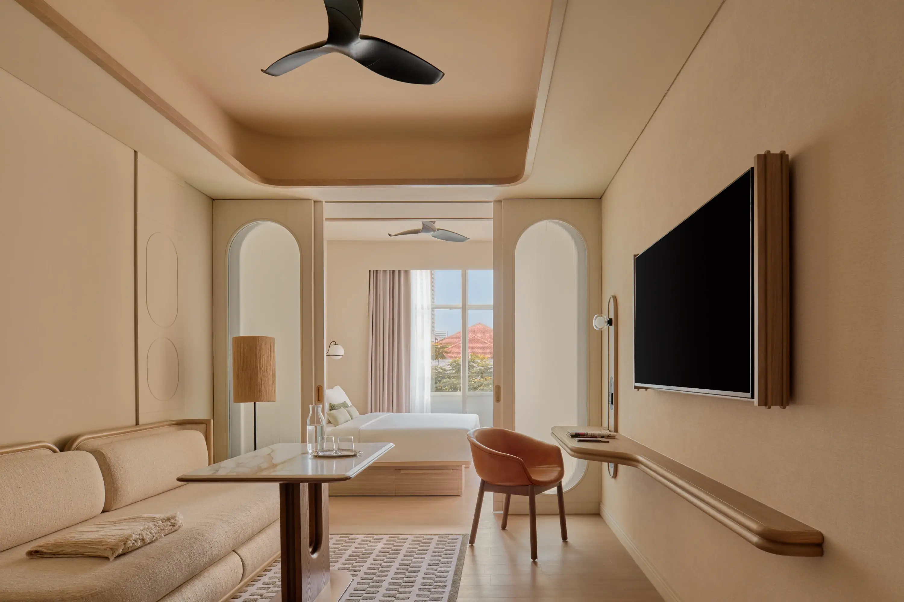 The Stamford Premier Suite living area with arched doorways looking through to the bedroom, terracotta rooftops and blue sky visible through the window beyond.