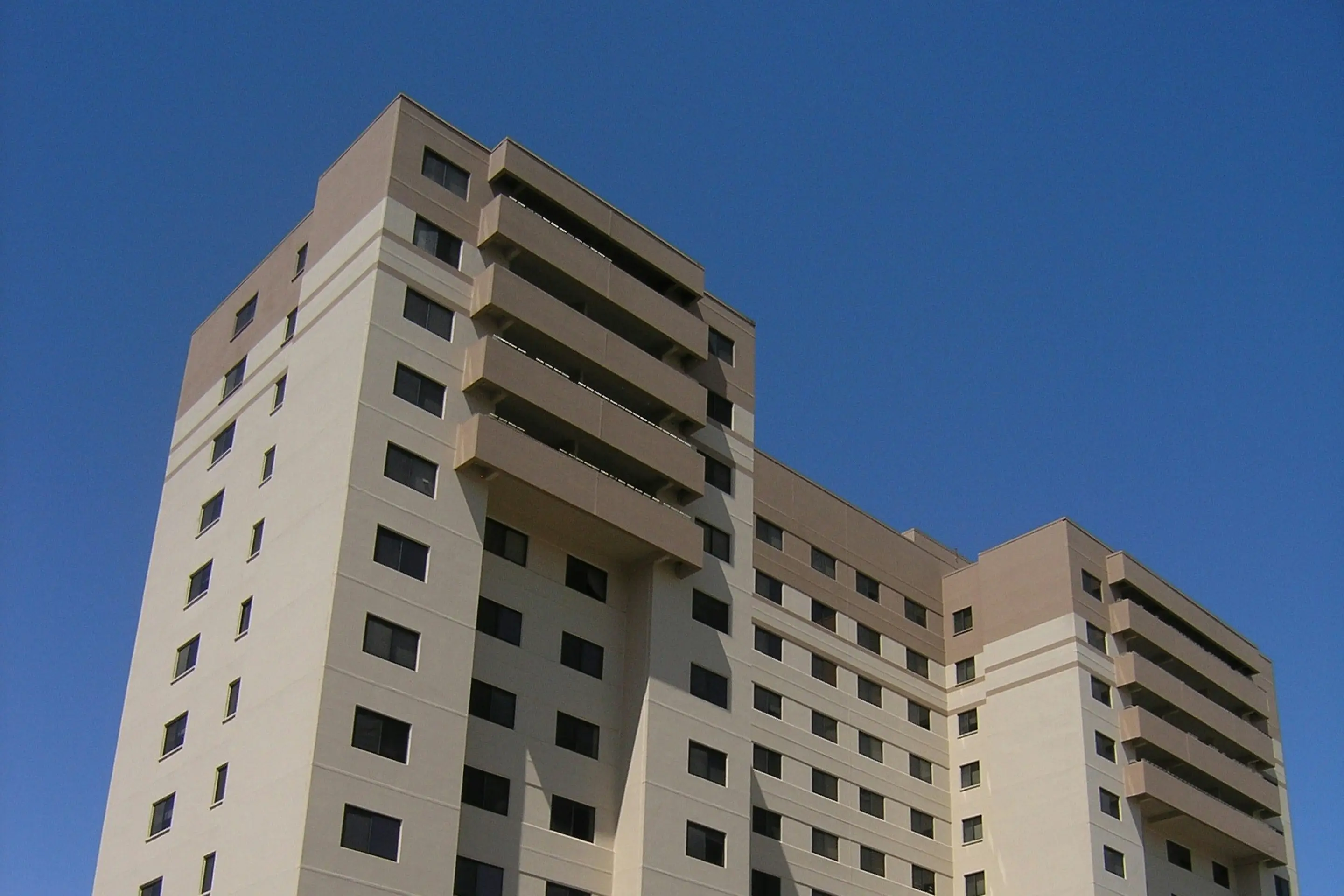 Modernes Wohnhochhaus mit heller Fassade vor blauem Himmel als Sinnbild für Wohnanlagen im Bereich Seniorenwohnen