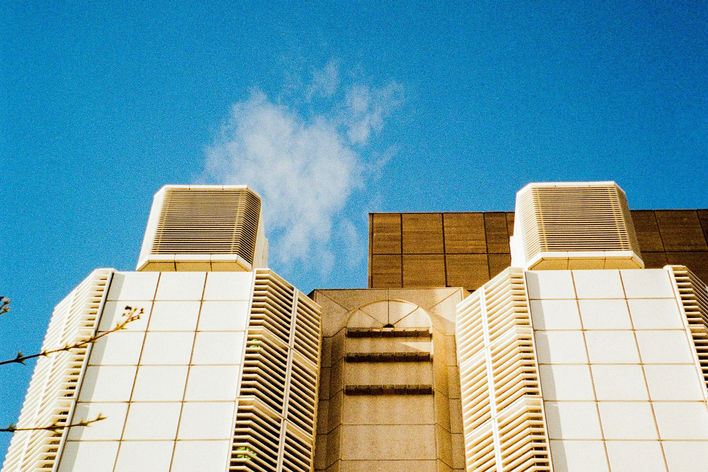 Monumentale Fassade eines Krankenhauses mit hellen Steinplatten und markanter Struktur vor blauem Himmel als Sinnbild für öffentliche Gebäude