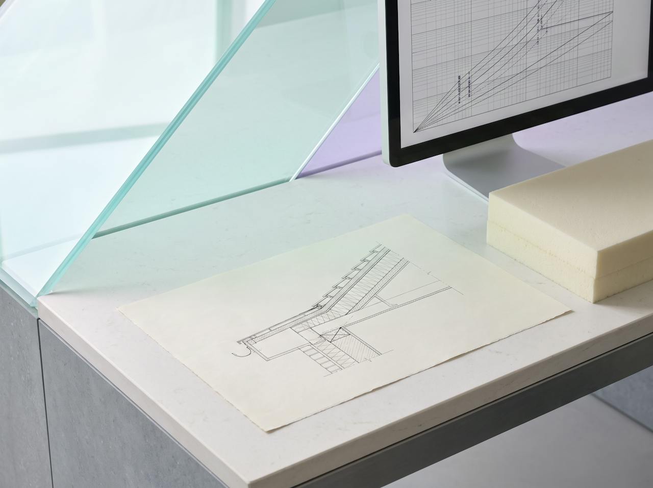 An engineer's desk in soft daylight: a roof build-up section drawing, a moisture chart on a screen and a cream closed-cell foam sample, with sea-glass and violet light falling across the paper.