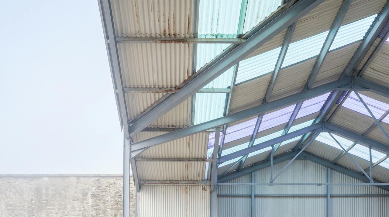 The underside of a corrugated sheet roof on purlins, seen from the floor.
