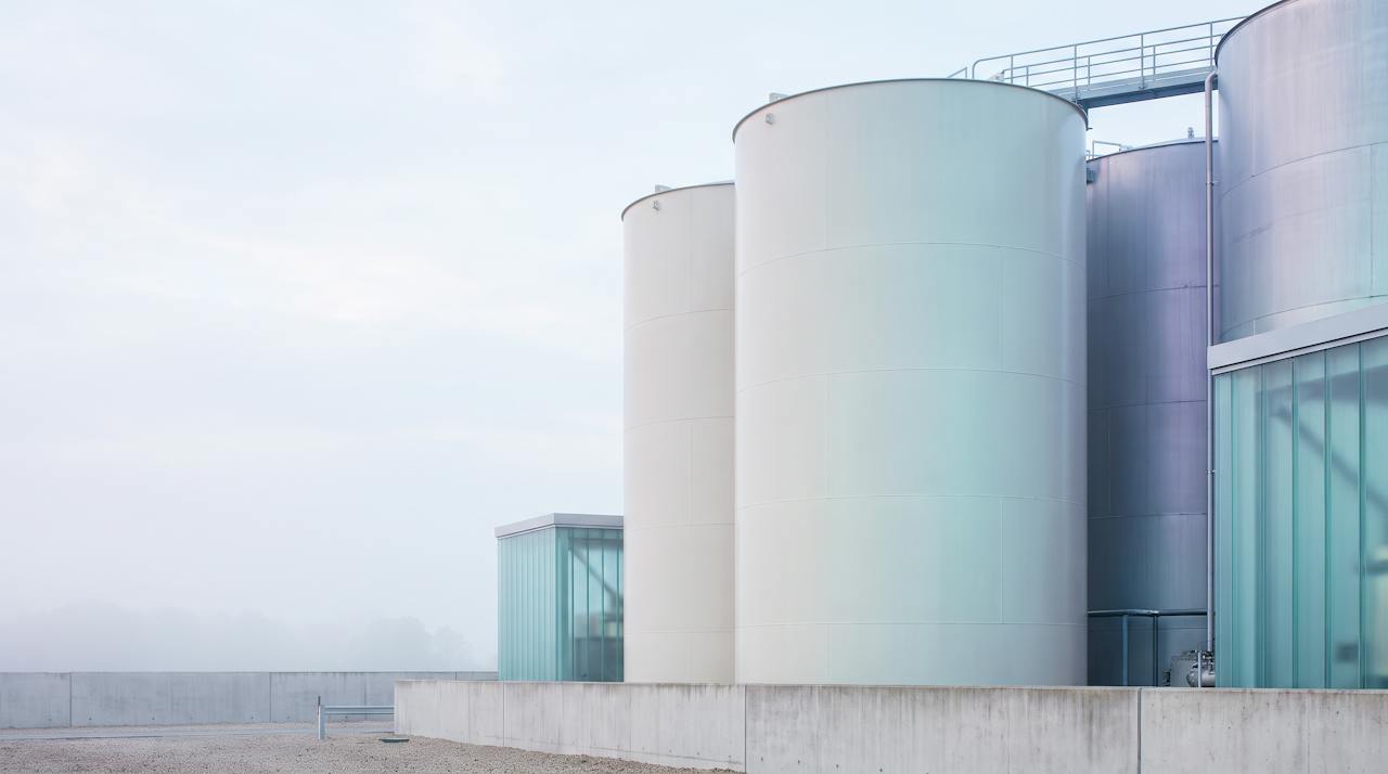 A steel storage tank in a plant yard under soft daylight.