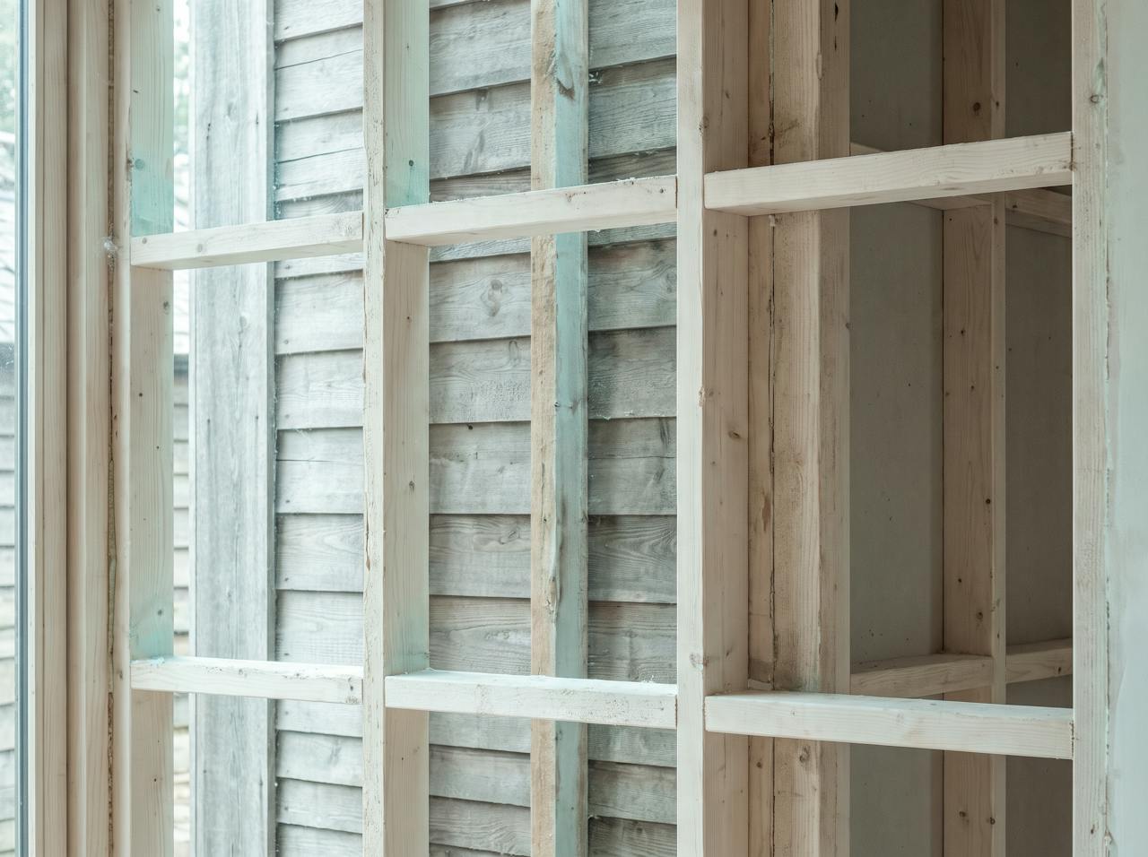 A close detail of the inside of a bare profiled metal wall between two cladding rails, fixing heads and a run of dark staining down the sheet.