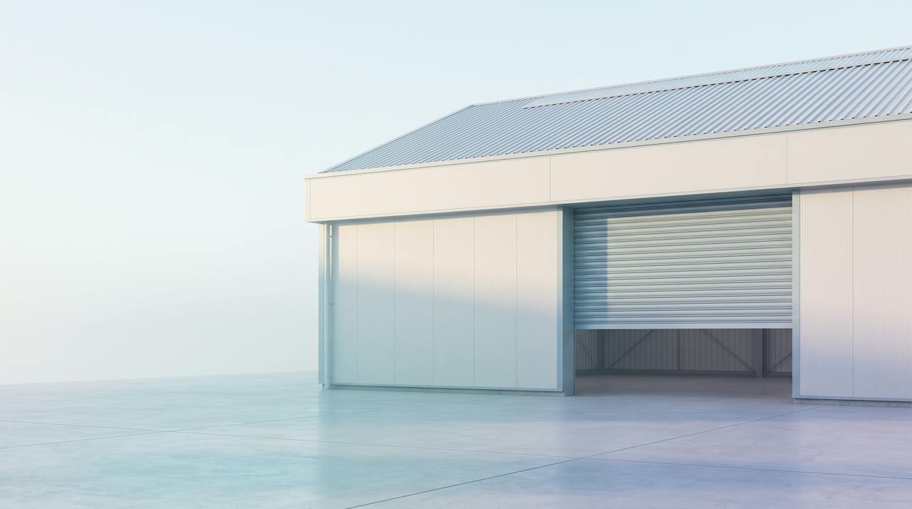 A vehicle workshop interior with a car on a ramp under a steel roof.