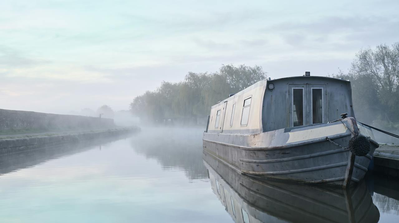 A steel narrowboat hull under cover in a boatyard.