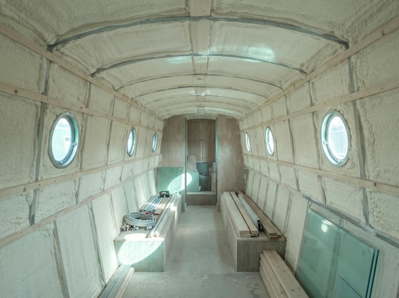 The same cabin after treatment: hull sides, cabin sides and roof lined in a continuous cream closed-cell layer between the battens, the bilge left clear.