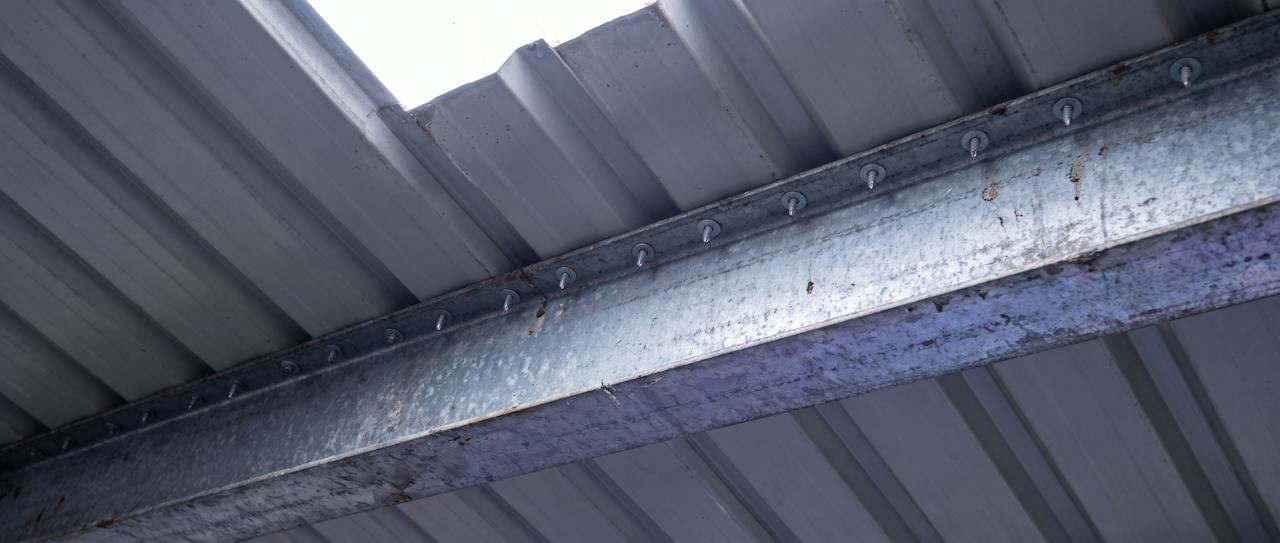 A cut section of a roof build-up beside a drawing and a calculator, in soft light.