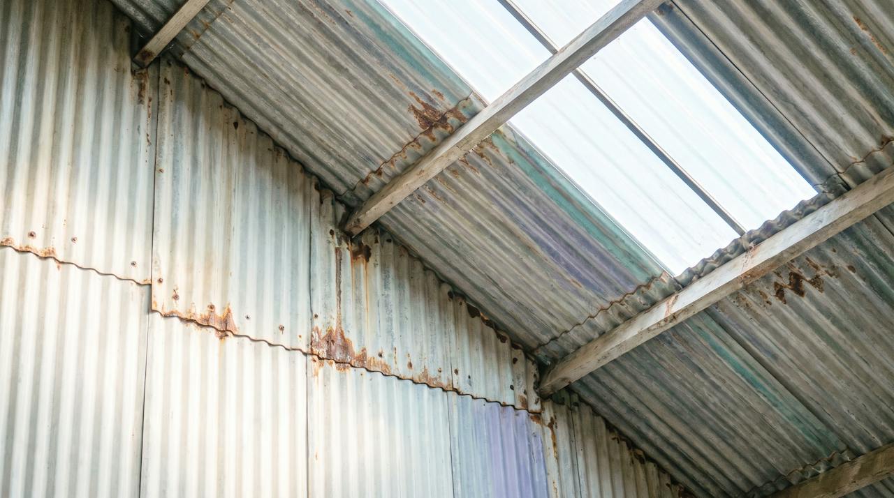Rust streaks running from the fixings down the underside of a profiled steel roof sheet, seen from below.