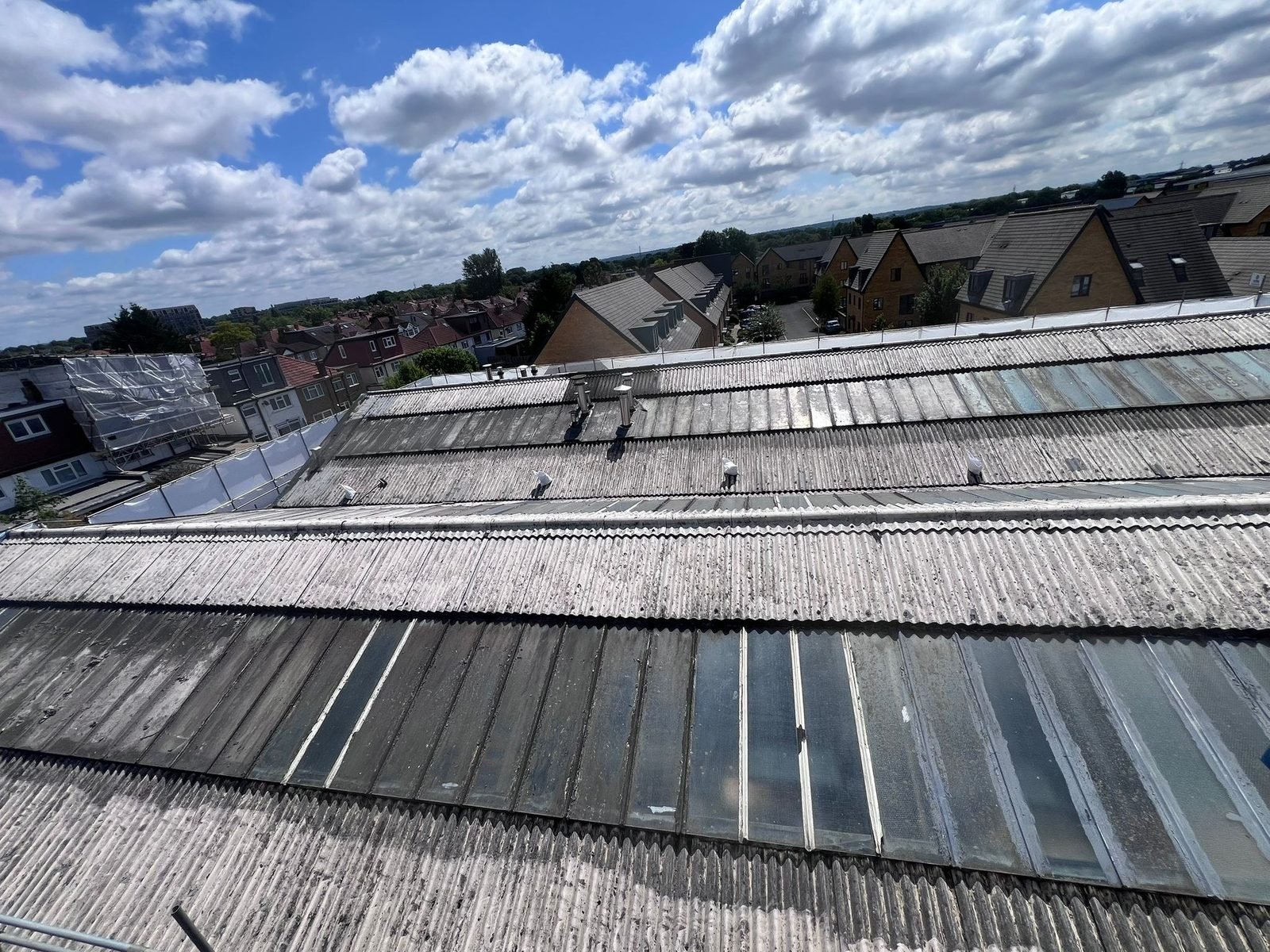 Before: the worn, stained asbestos-cement roofs of Global House, moss in the troughs.