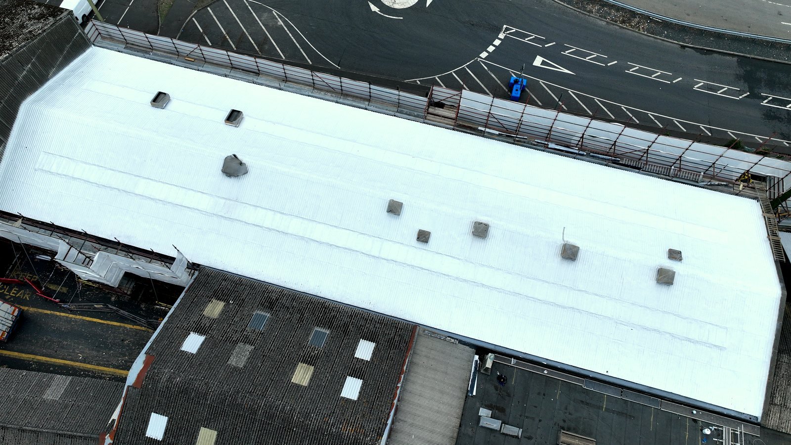 SAICA Warrenpoint from the air: the completed Unit 3 roof under one coated surface beside the untreated bays.