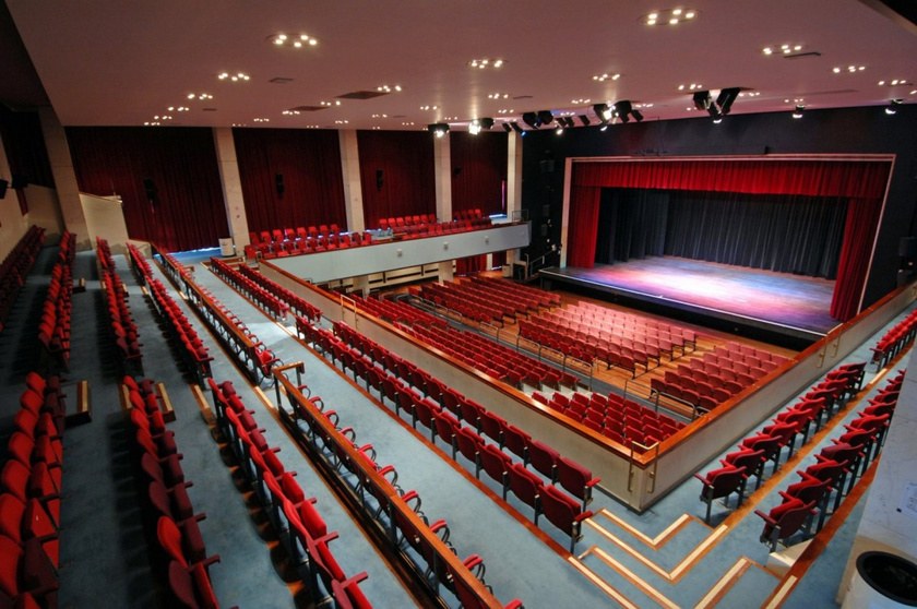The Alban Arena auditorium from the balcony: raked red seating and a lit stage.