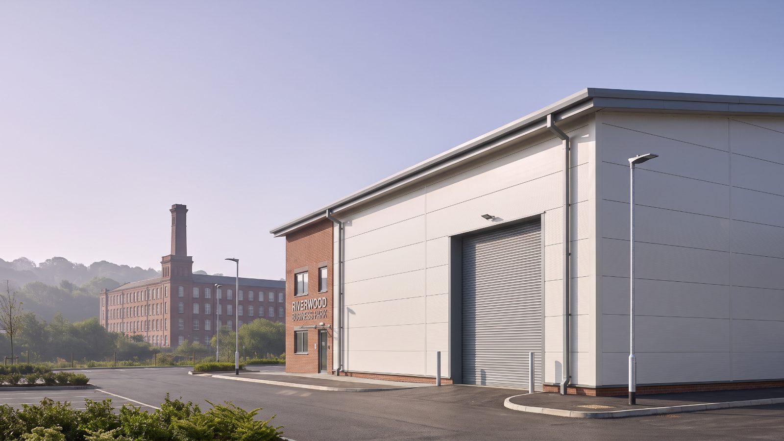 A new pale industrial unit with a single loading door, a tall Victorian cotton mill with a square chimney.