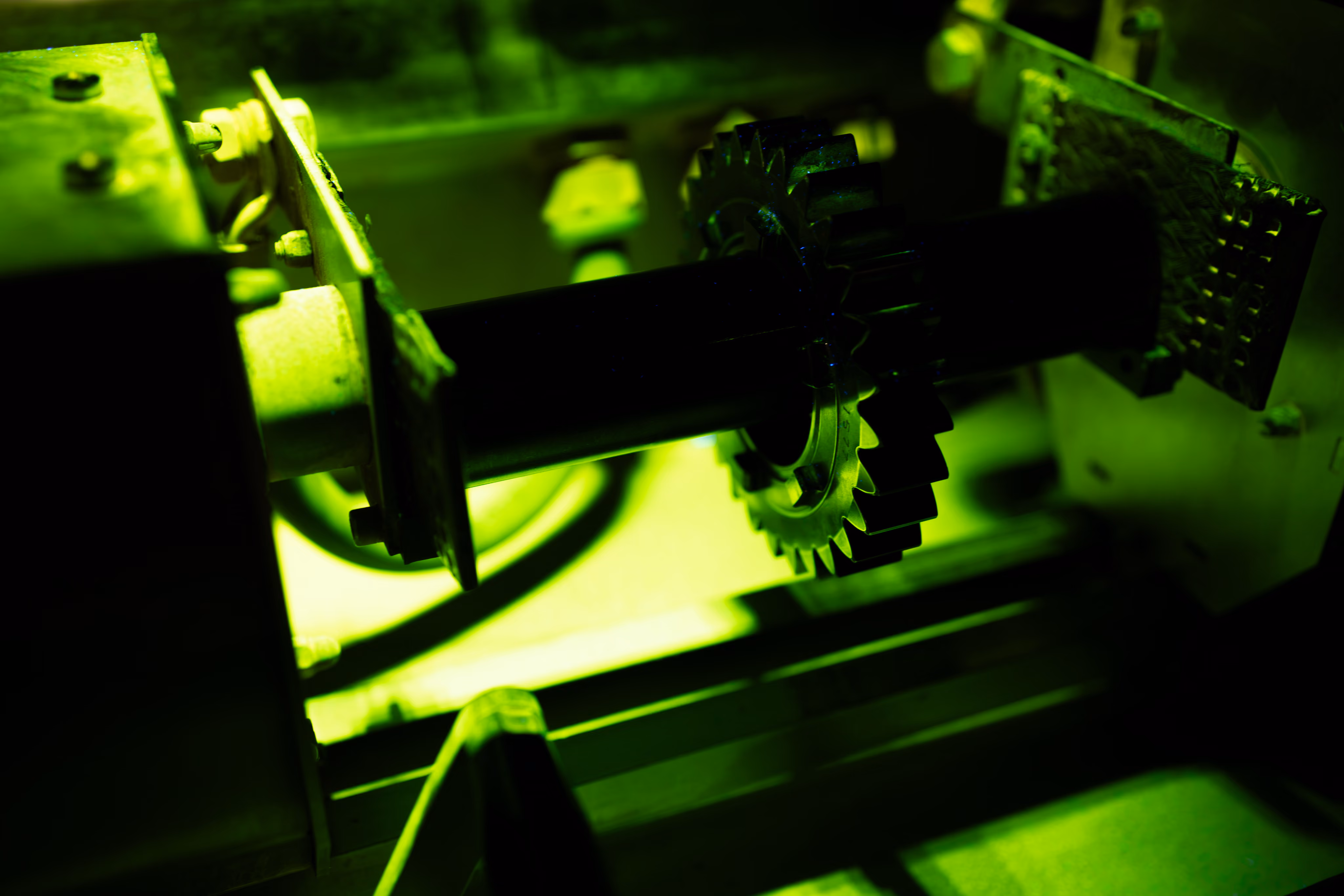 Nahaufnahme eines Metallzahnrads an einer Maschine mit grünem Licht.