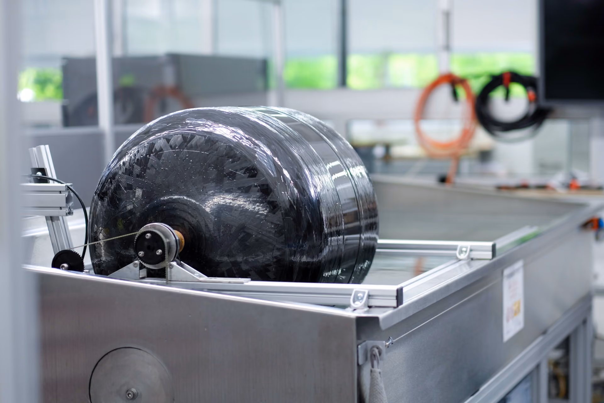 Große schwarze Rolle aus Kohlefaser-Verbundmaterial auf industrieller Prüfanlage.