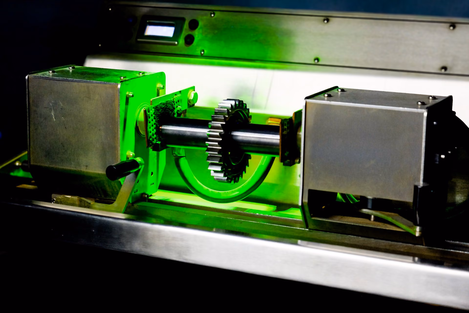 Metallgetriebe mit Zahnrädern wird in Prüfanlage unter grünem Schwarzlicht getestet.
