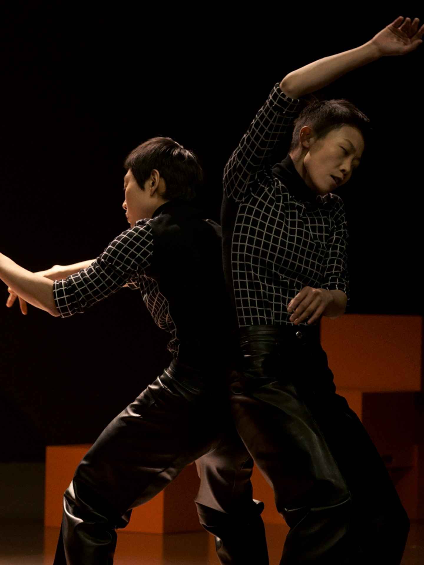 Two dancers in checked shirts and leather trousers in a close duet, Hermès show in Shanghai