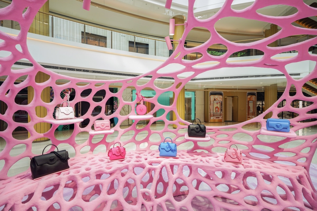 Handtaschen in Pink, Blau und Schwarz in den Öffnungen der korallenartigen Versace-Installation
