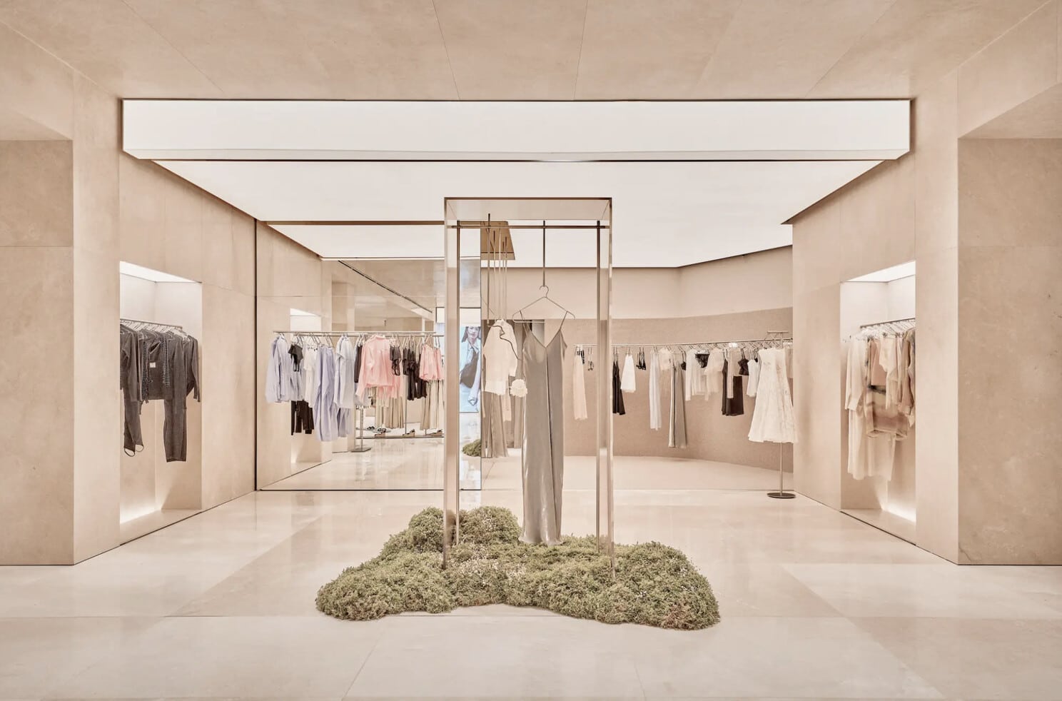 Heller Boutique-Showroom mit Kleiderständern und moosbewachsenem Präsentationssockel
