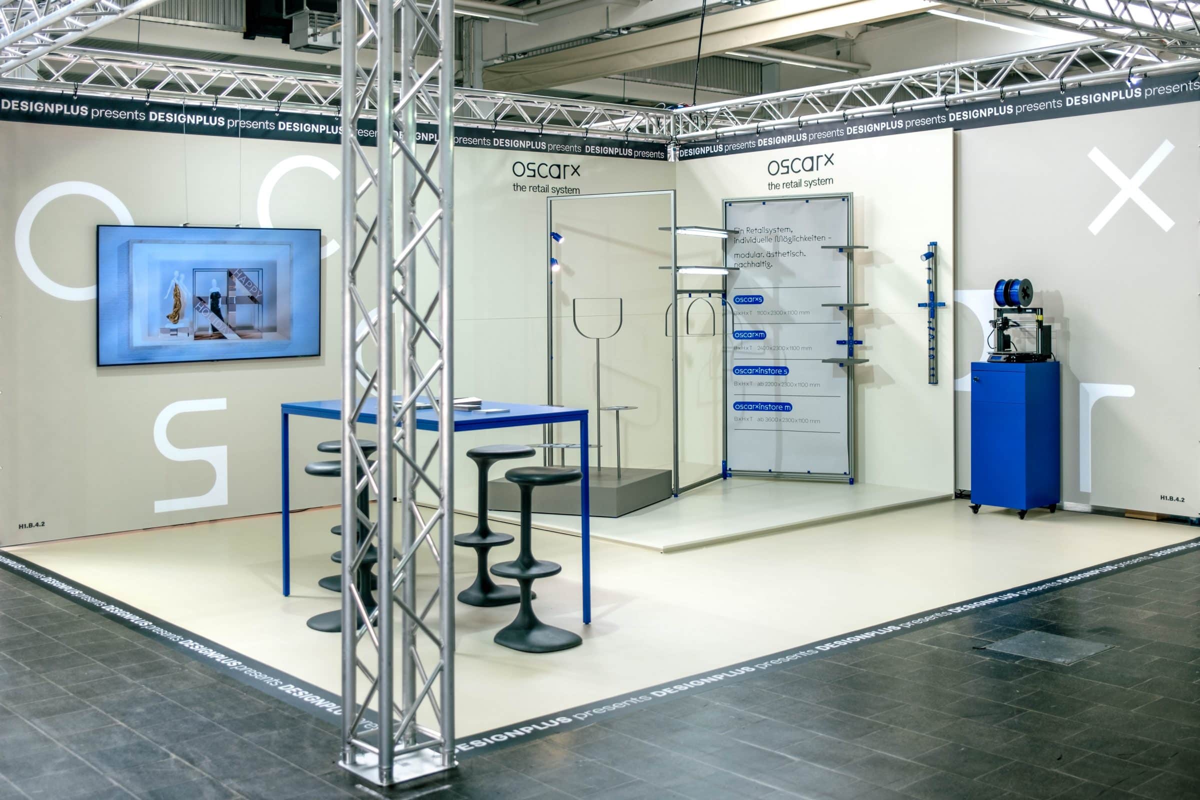 oscarx-Messestand von Designplus mit Sitzbereich und Präsentationswänden