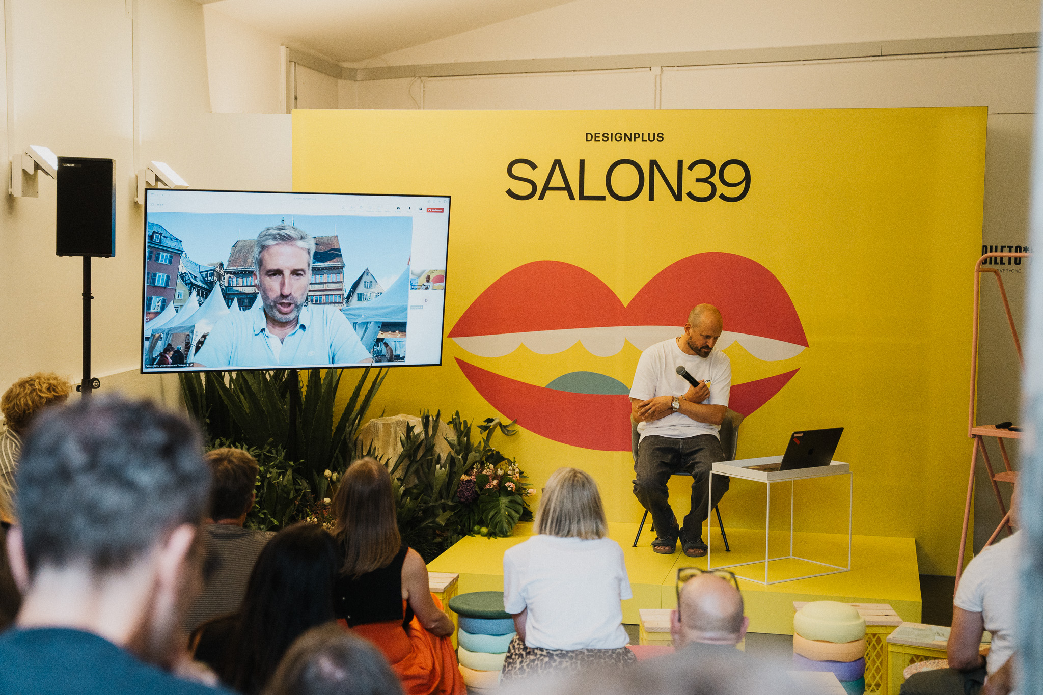 Speaker auf der SALON39-Bühne im Video-Talk mit einem Gast auf der Leinwand