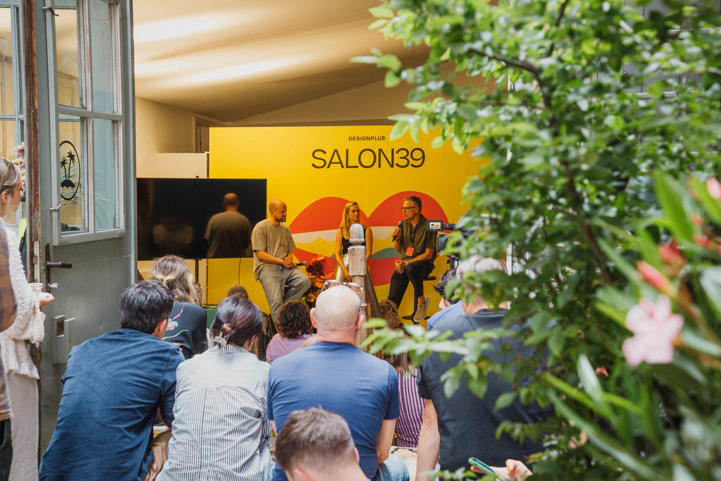 A panel discussion with three speakers in front of the SALON39 backdrop in the garden setting.