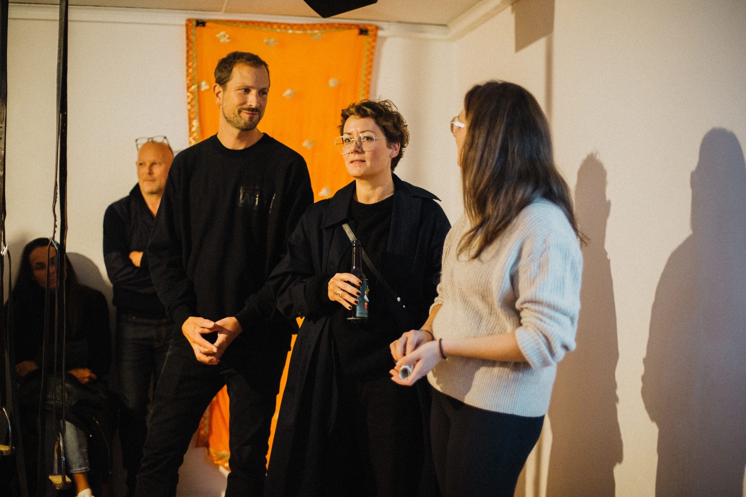 Guests chat in front of an orange fabric backdrop at the Lange Nacht der Nachhaltigkeit
