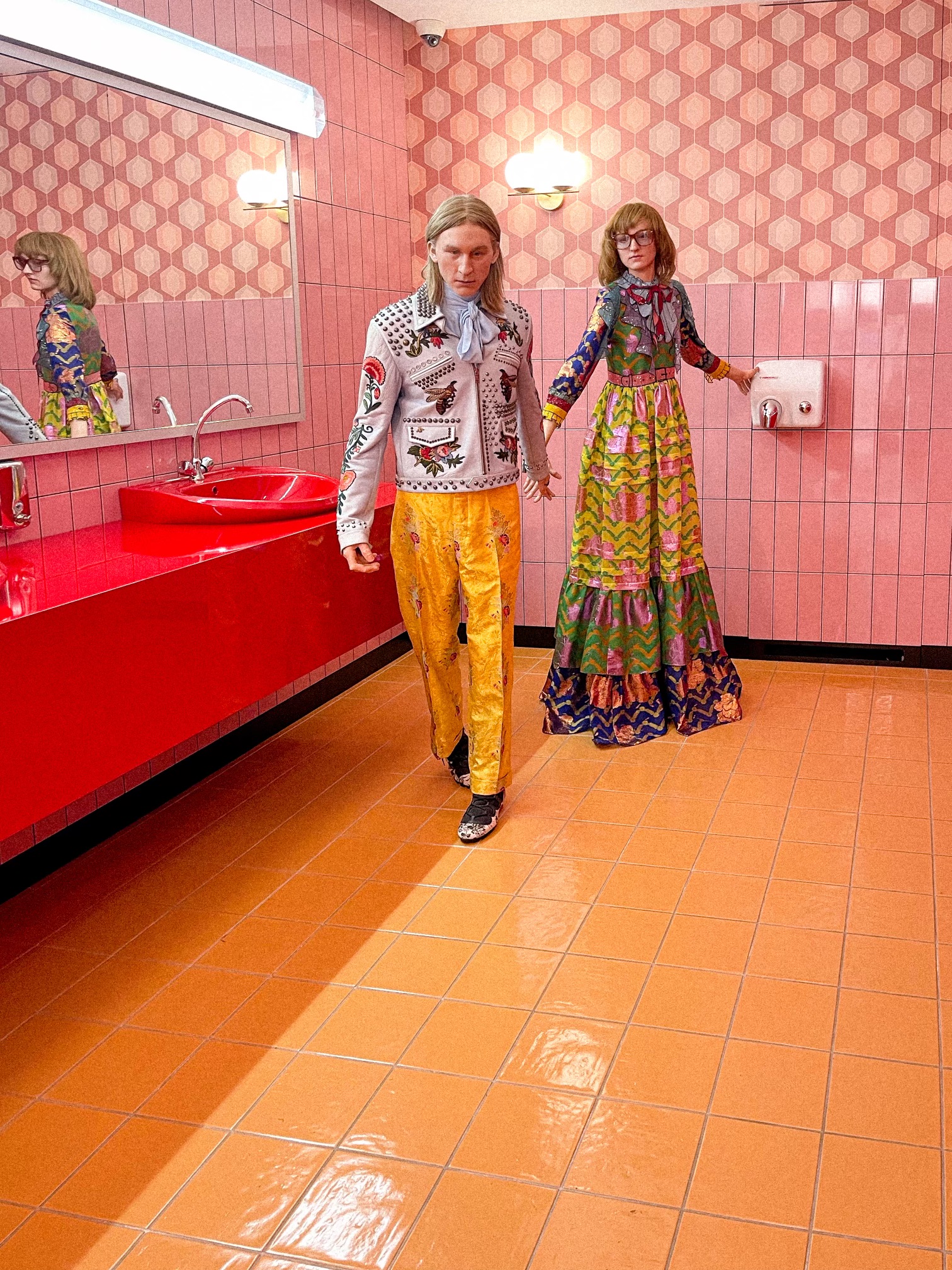 Models in colourful Gucci outfits in a kitschy pink bathroom set, installation at Milan Design Week