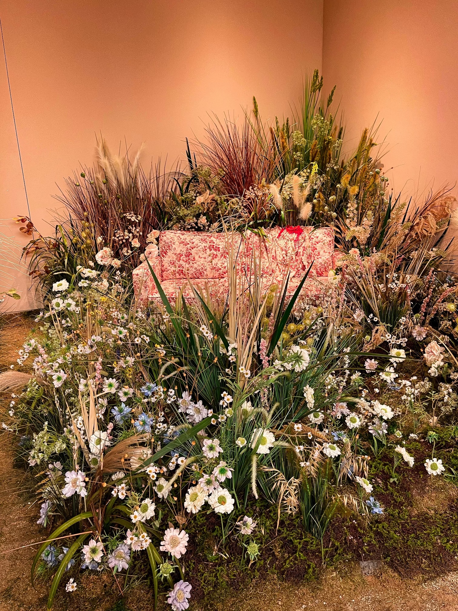 Vintage floral sofa embedded in a lush dried-flower-and-grass installation