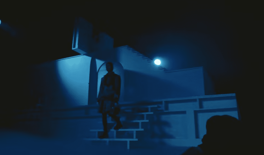Model schreitet über beleuchtete Treppe in bläulich inszenierter Bühnenkulisse der Show