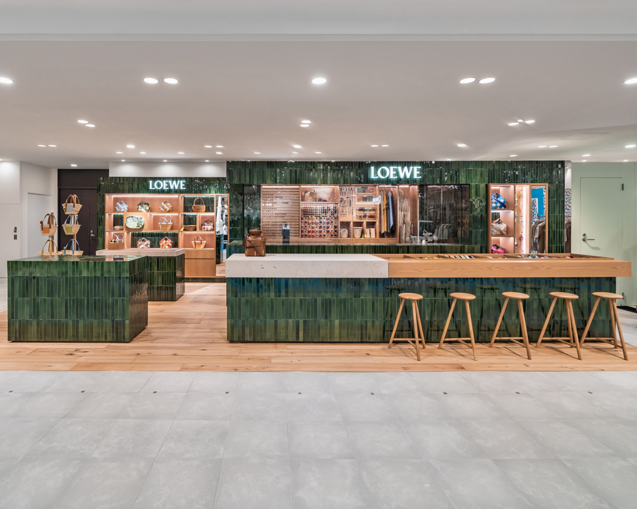Loewe store with green-tiled counters and an illuminated brand sign