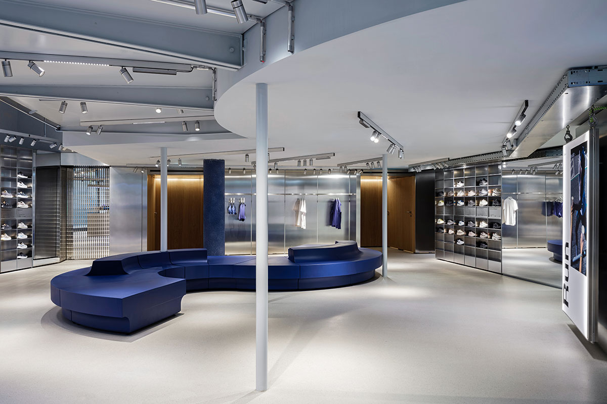 Minimalist On store with a curved blue bench and metallic shelving walls