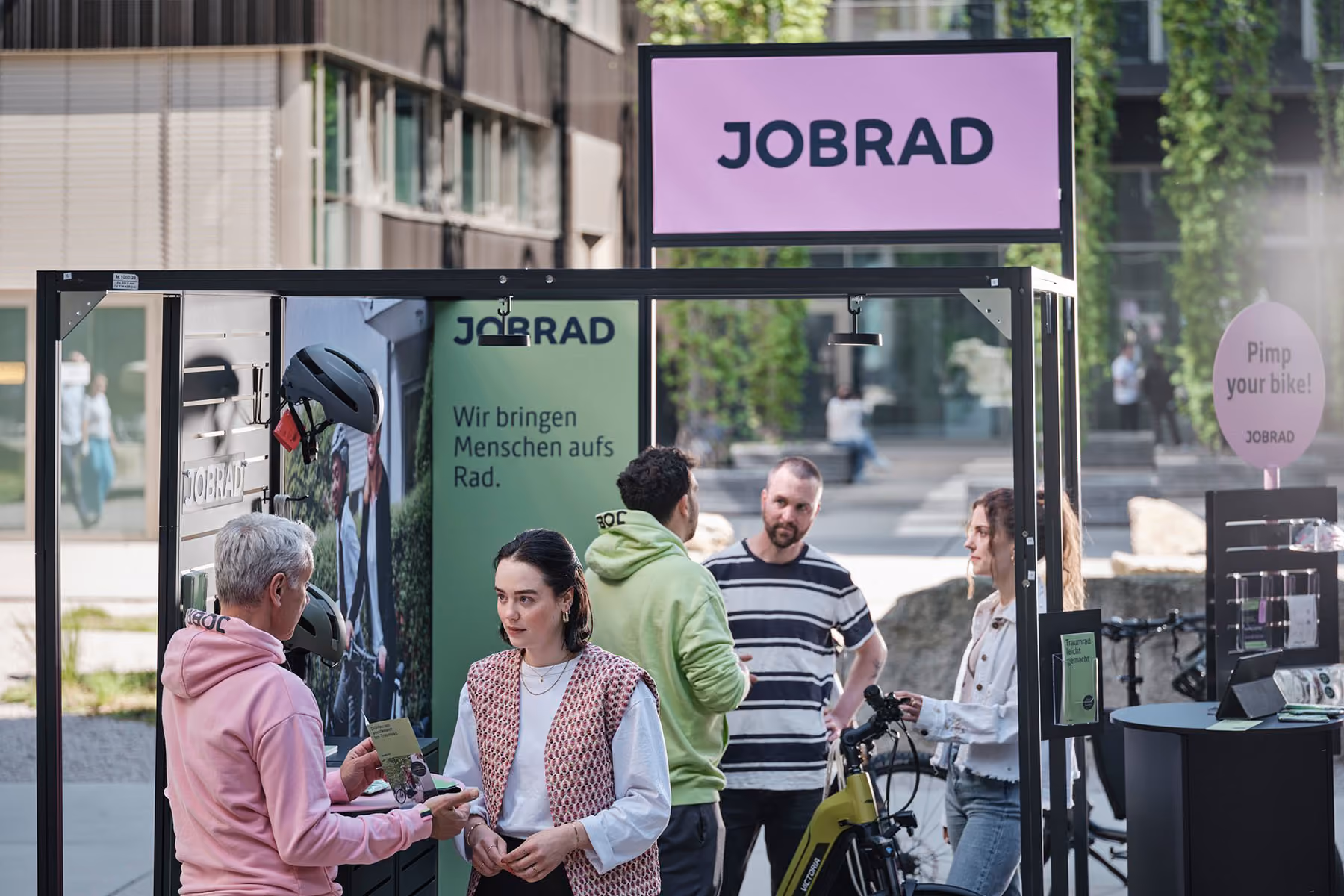 JobRad-Infostand mit Beratungstheke, Besucher im Gespräch mit dem Team neben einem E-Bike