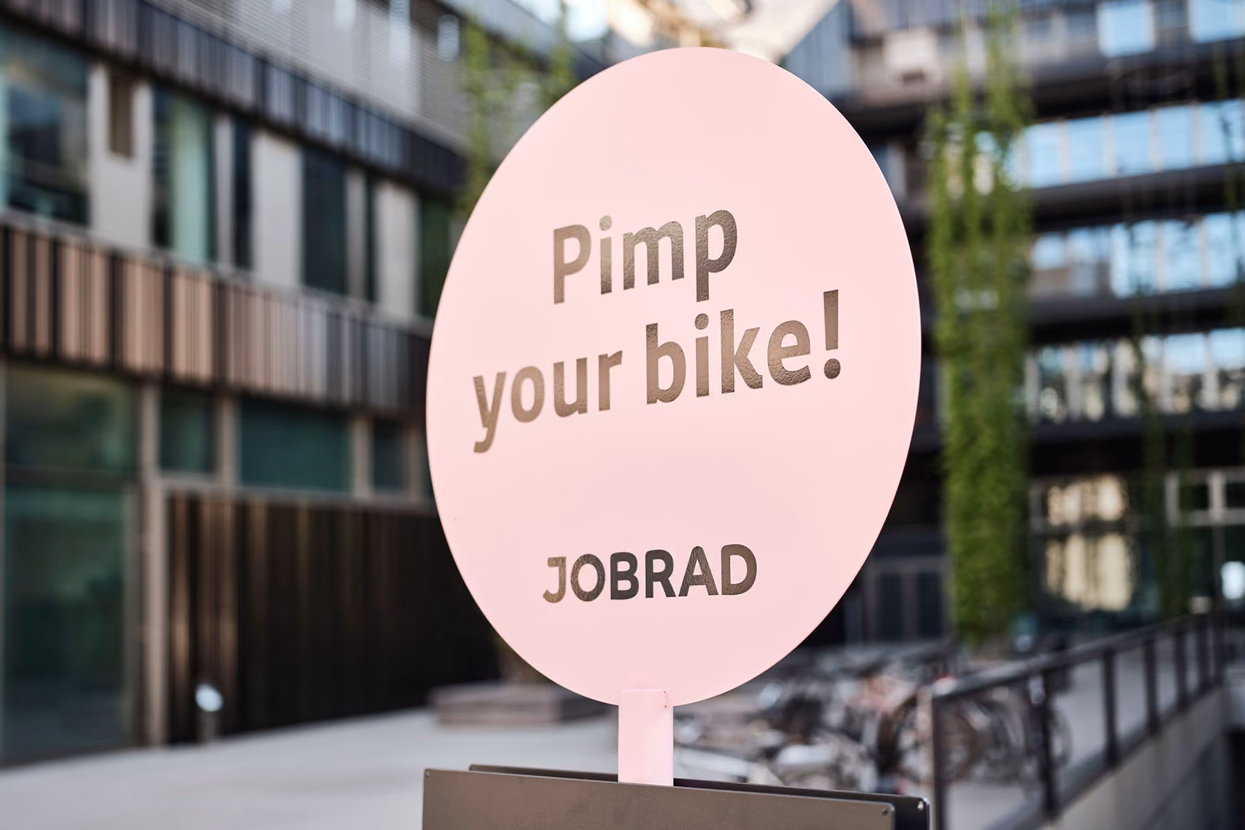 Rundes Schild „Pimp your bike! JOBRAD“ auf einem Ständer im Freien