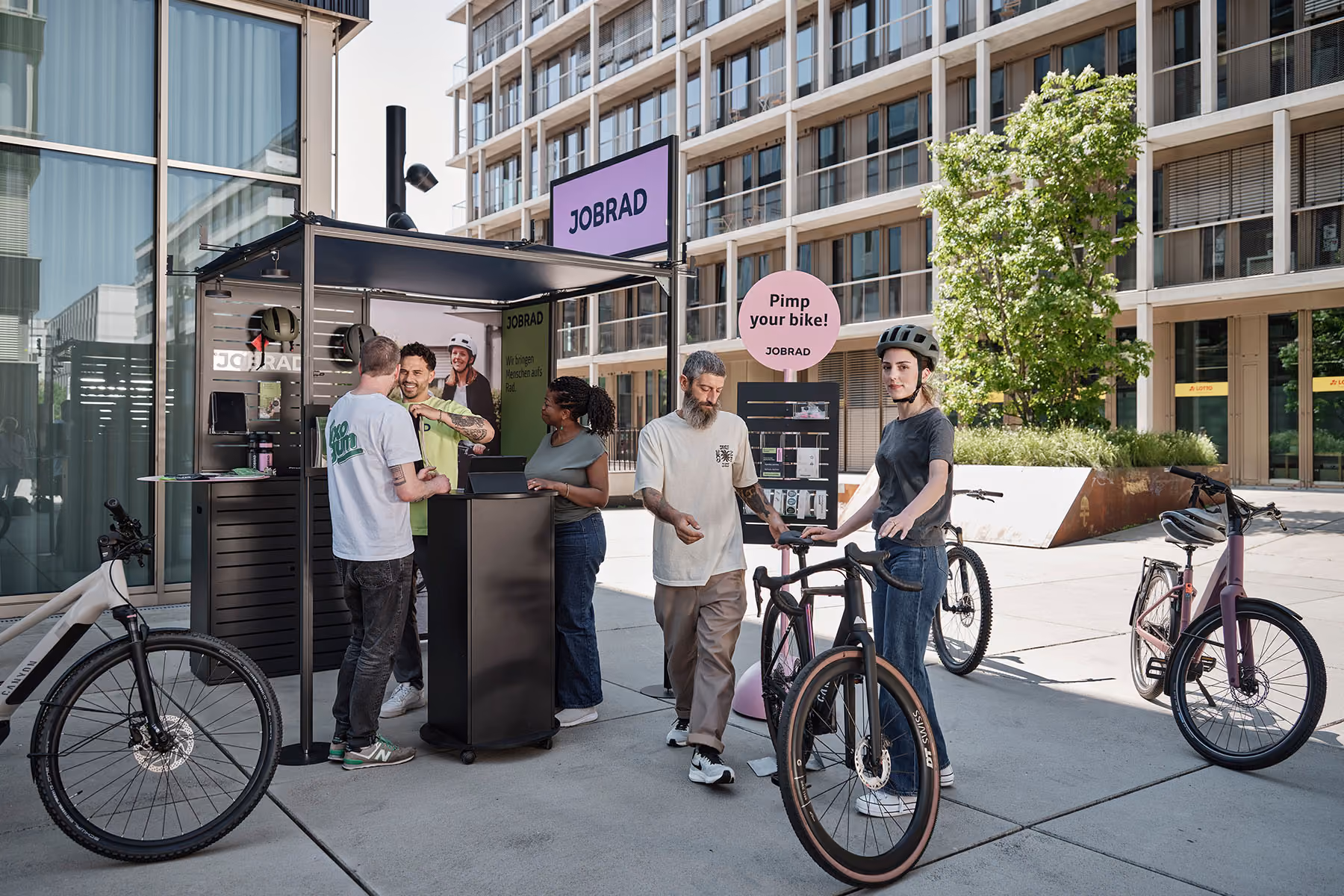 Besucher mit Fahrrädern und Helmen am JobRad-Stand neben dem Schild „Pimp your bike!“