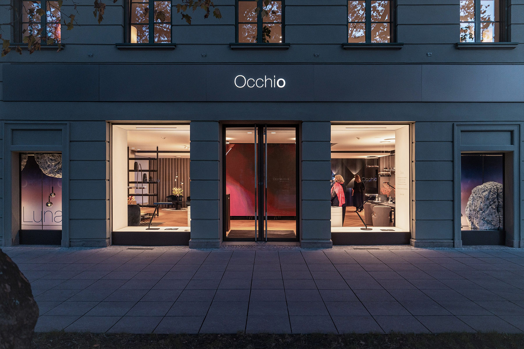 Occhio storefront at dusk with illuminated windows and the "Luna" light installation visible