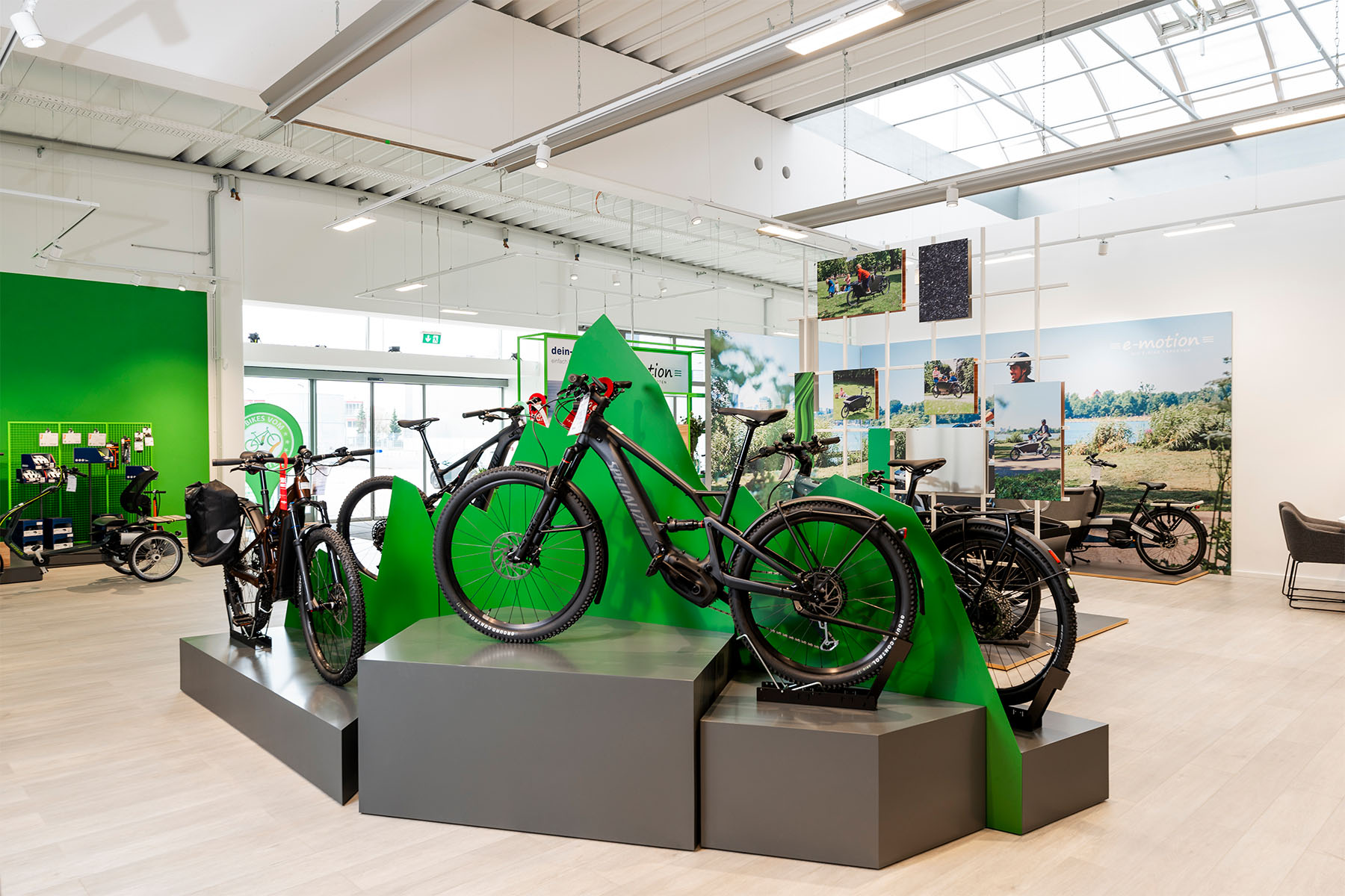 E-bikes displayed on green mountain-shaped pedestals in the open e-motion store