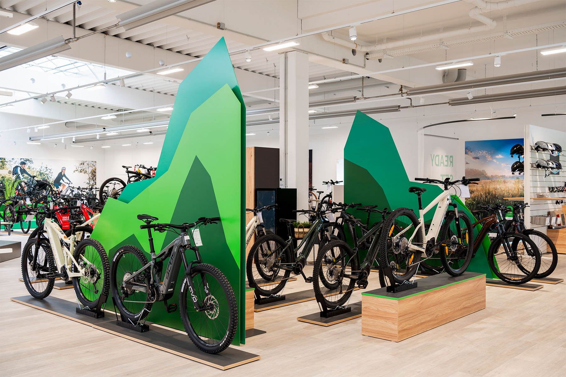 Selection of e-bikes on the green mountain pedestals across the open sales floor