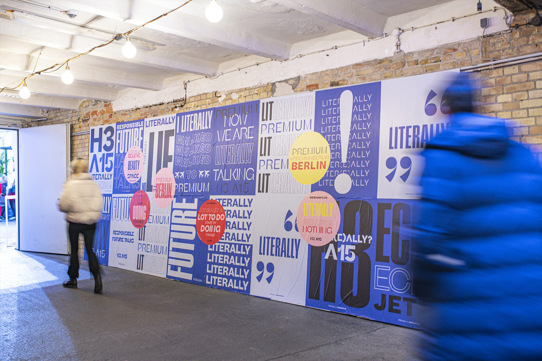 Besucher gehen an einer typografischen Wandcollage „Literally/Premium Berlin“ vorbei.