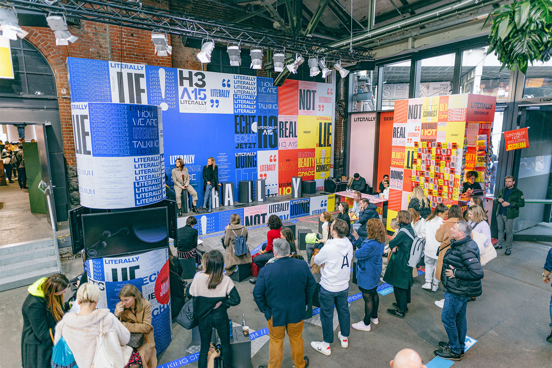 Speaker Area „Literally Real“: bunte Typo-Wände in Blau, Rot und Gelb, davor Publikum.