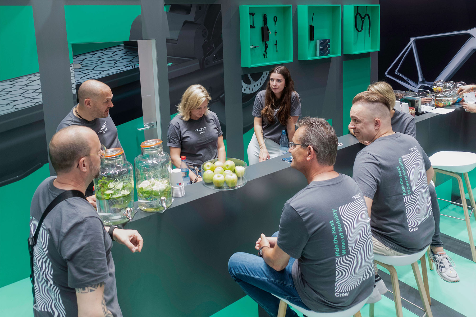 Egret-Crew im grauen Team-Shirt an der Stehbar des Messestands im Gespräch mit Besuchern.