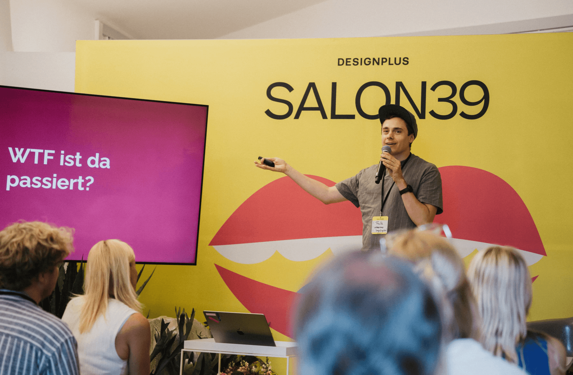 Speaker mit Mikrofon vor der Frage „WTF ist da passiert?" auf der SALON39-Bühne